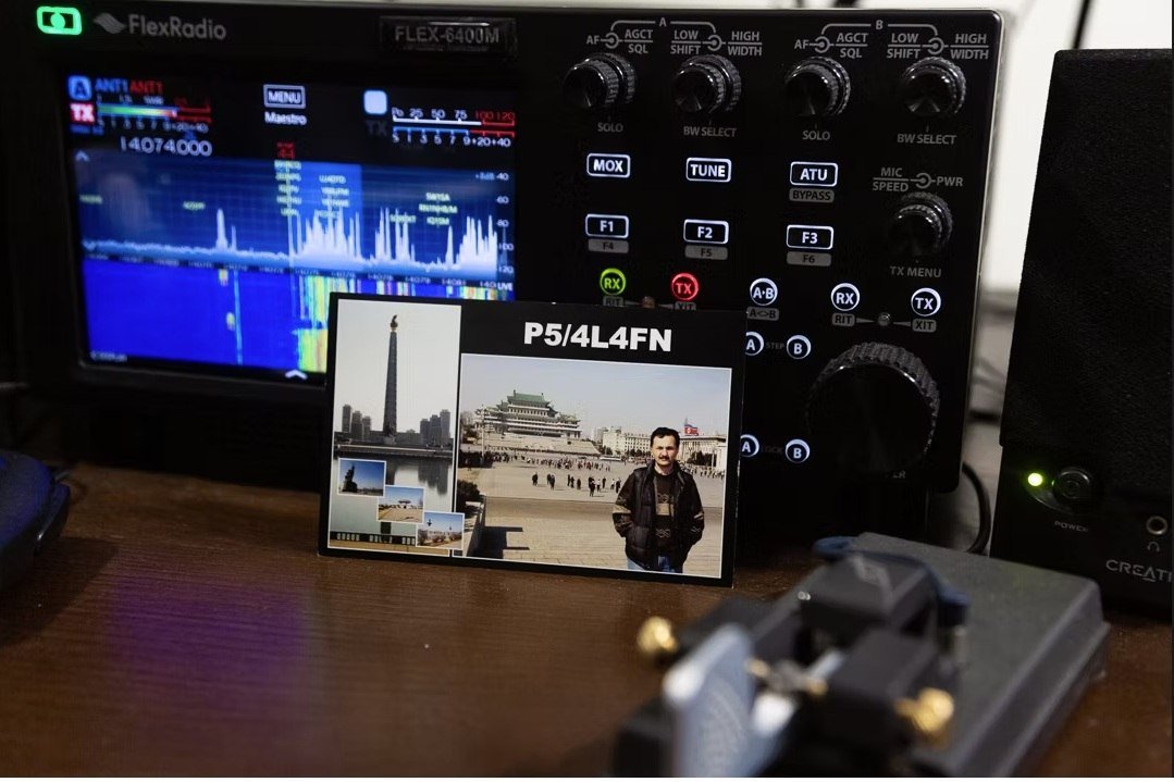 Cartão QSL de P5/4L4FN, da Coreia do Norte, junto a um rádio e a uma chave