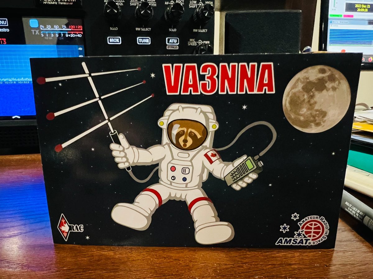 Cartão QSL de VA3NNA, do Canadá, com um astronauta a segurar uma antena Yagi e um rádio portátil